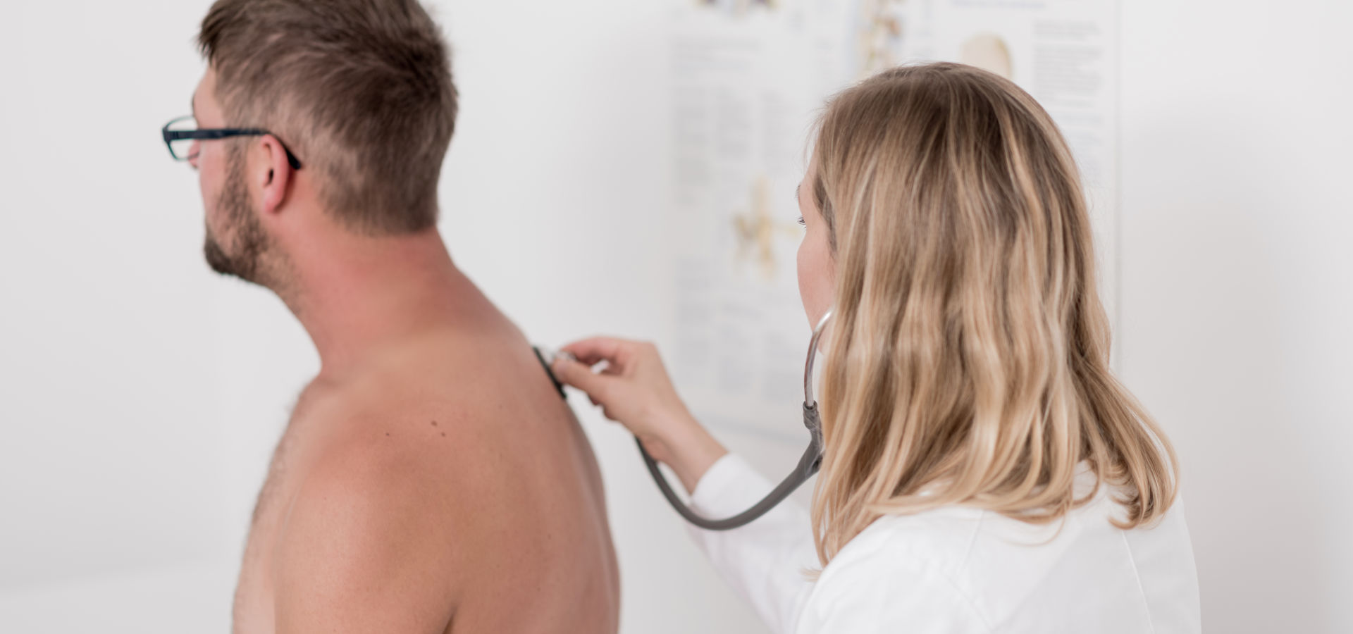 Dr. Janina Ledderose hört am Rücken einen männlichen Patienten mit dem Stethoskop ab